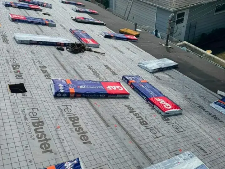 Roof underlayment with packaged asphalt shingles staged for installation