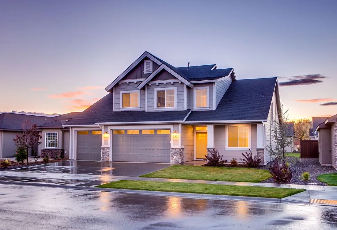 Shingle-roofed suburban home illuminated at dusk