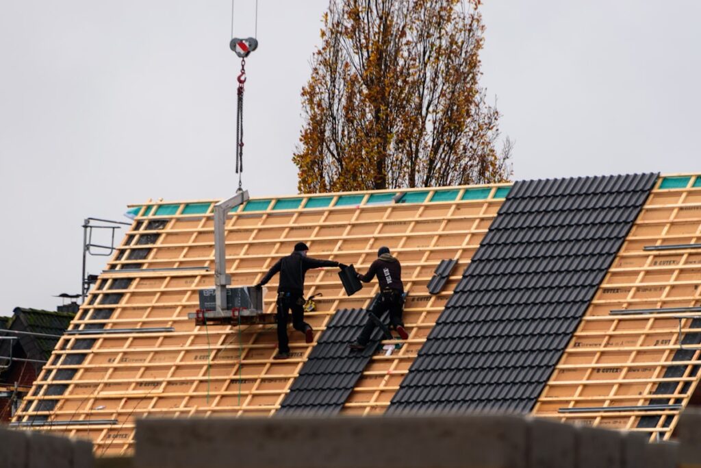 Construction workers installing roof tiles on a new building